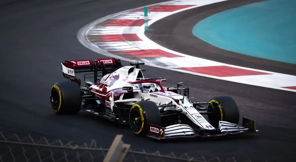 Auto da corsa in curva su circuito, con dati telemetrici sugli schermi in background