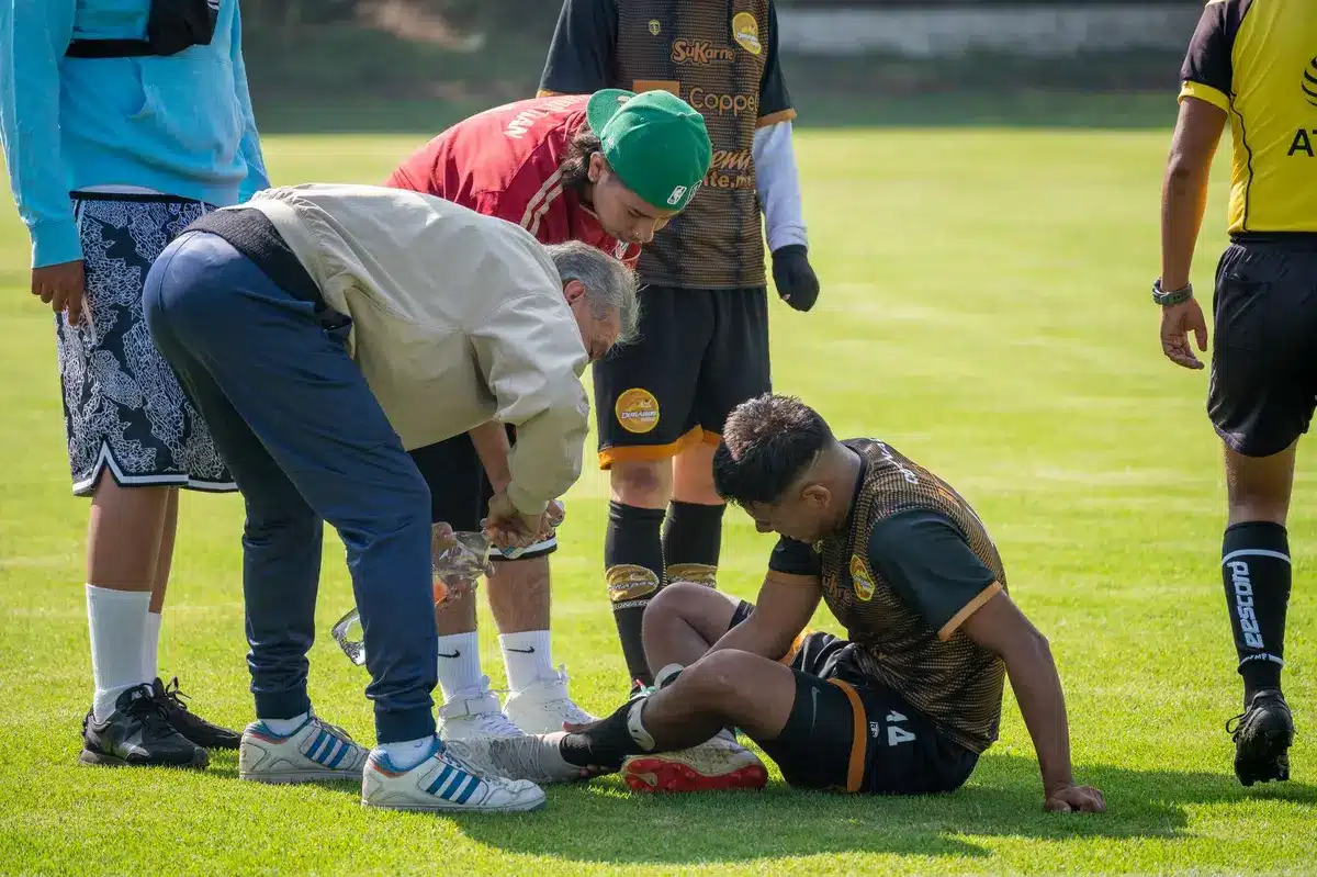 Giocatore di calcio in allenamento con il fisioterapista durante la seduta di gruppo