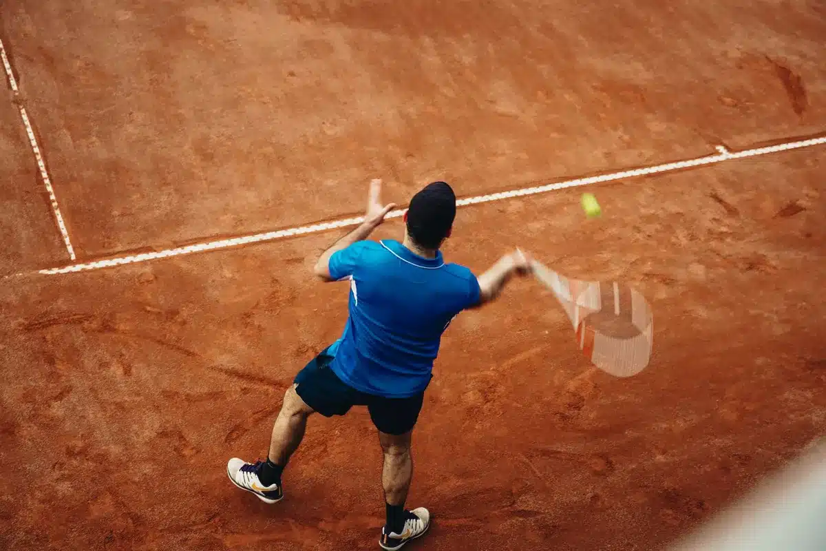 Tennista durante il servizio su campo in cemento con massima concentrazione
