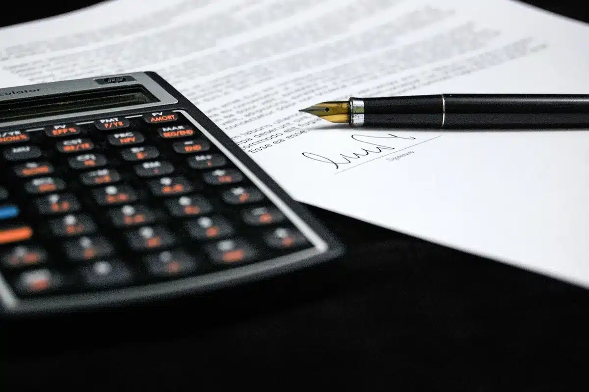 Contratto di trasferimento calcistico con documenti su scrivania e penna pronta alla firma