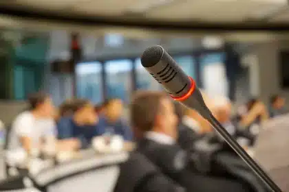 Sala conferenze con microfono vuoto e cartelle sul tavolo