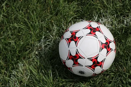Dirigente con plastico del campo e documenti, giovani giocatori sullo sfondo in riunione