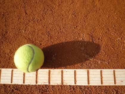 Campo da tennis al tramonto con racchette appoggiate vicino alla rete e una pallina a terra