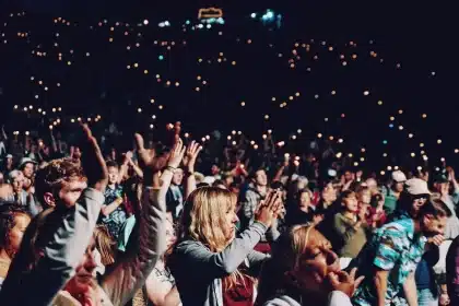 Folla anonima vista di spalle davanti a grandi schermi in uno stadio urbano