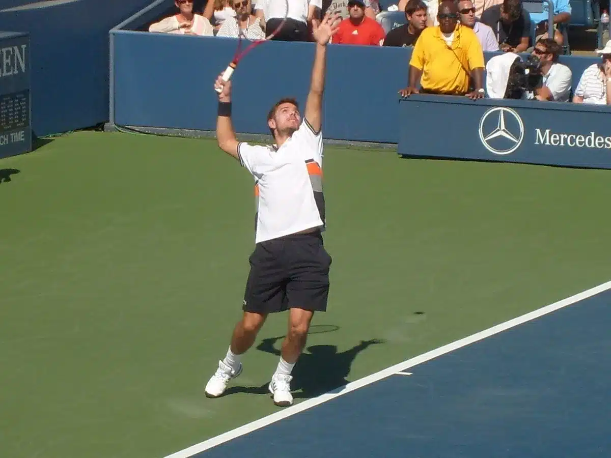 Tennista in azione durante un servizio su campo in cemento