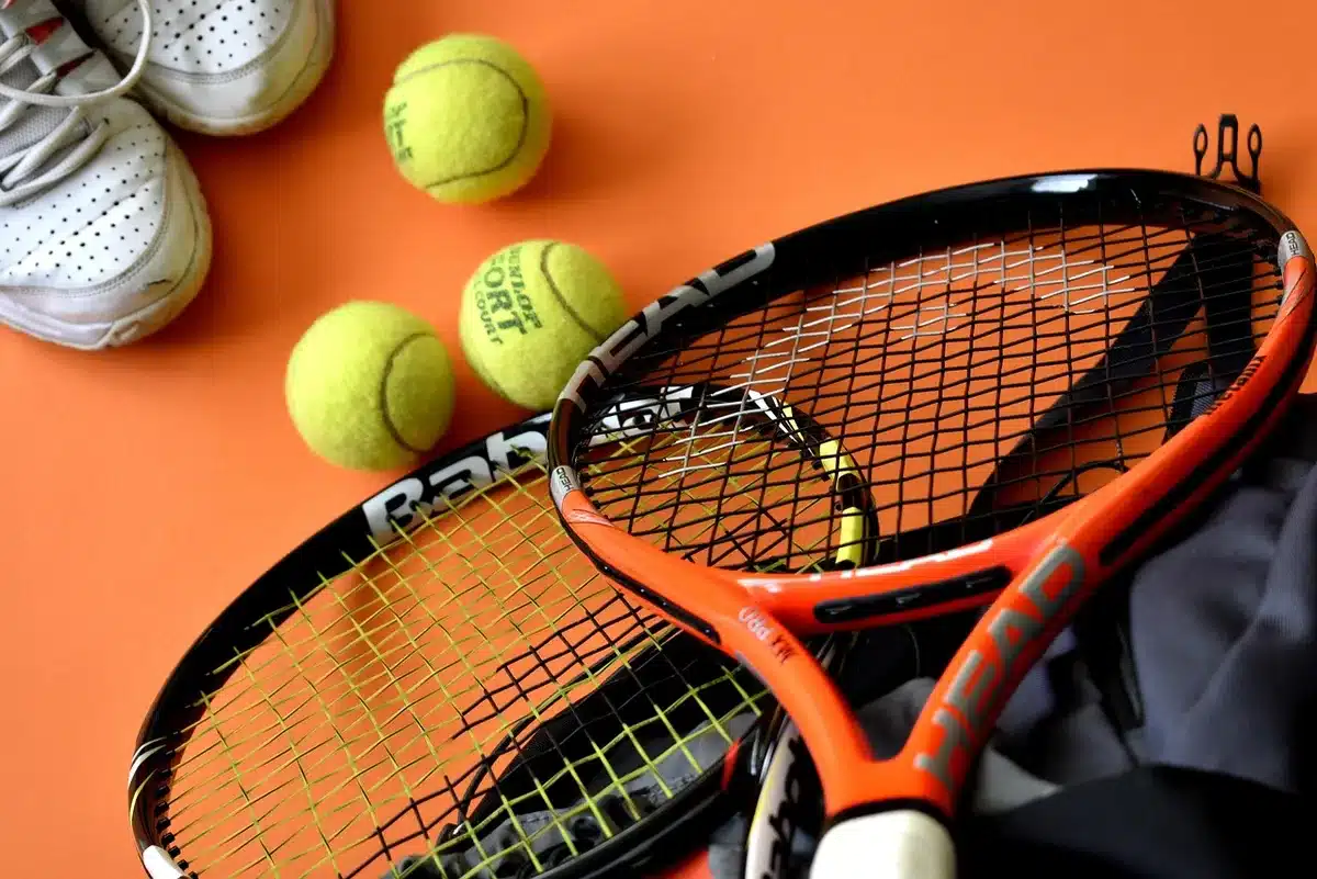 Campo da tennis con racchetta appoggiata e palline sparse, pubblico sfocato