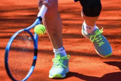 Campo da tennis al tramonto con trofeo su un tavolo e racchetta appoggiata, pubblico sfocato