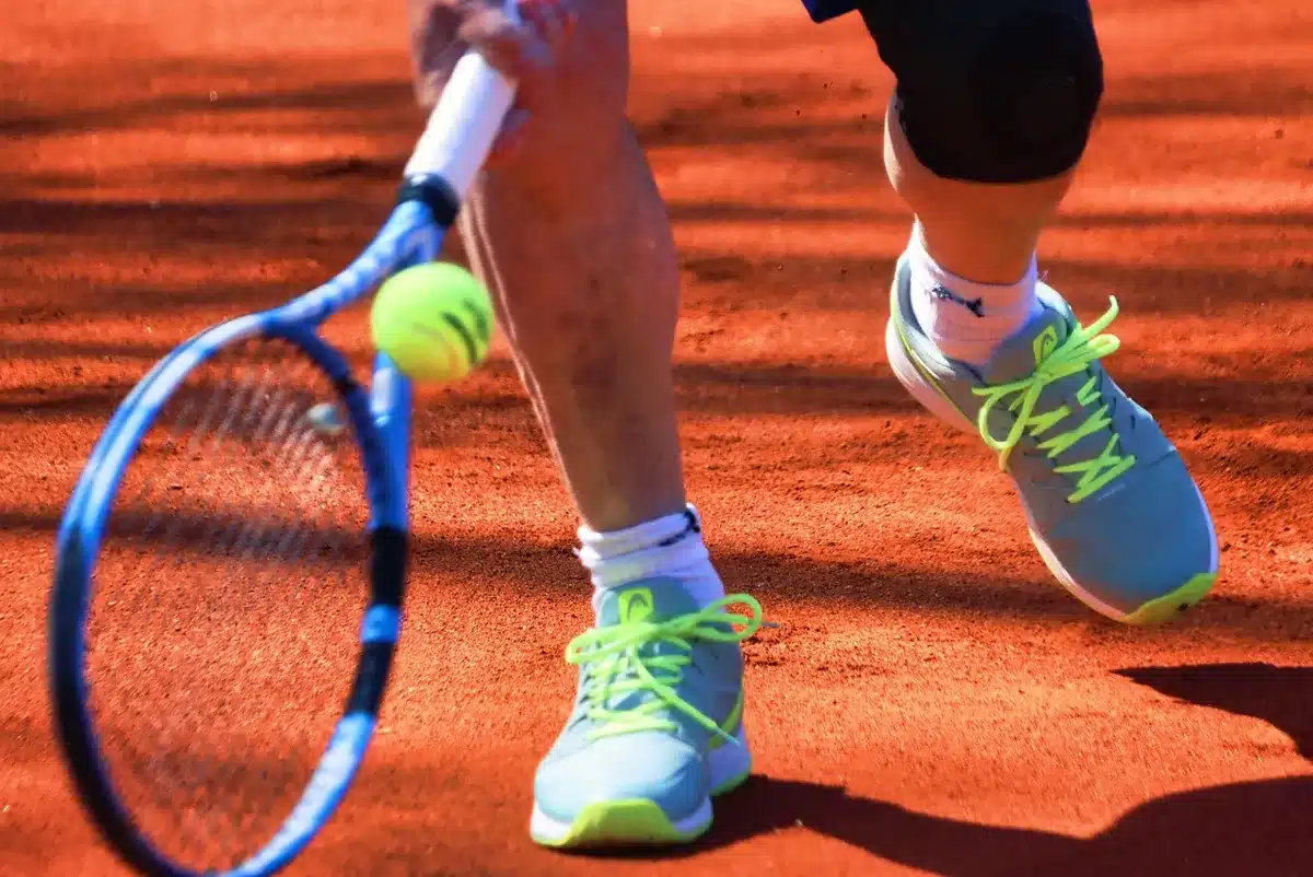 Campo da tennis al tramonto con trofeo su un tavolo e racchetta appoggiata, pubblico sfocato