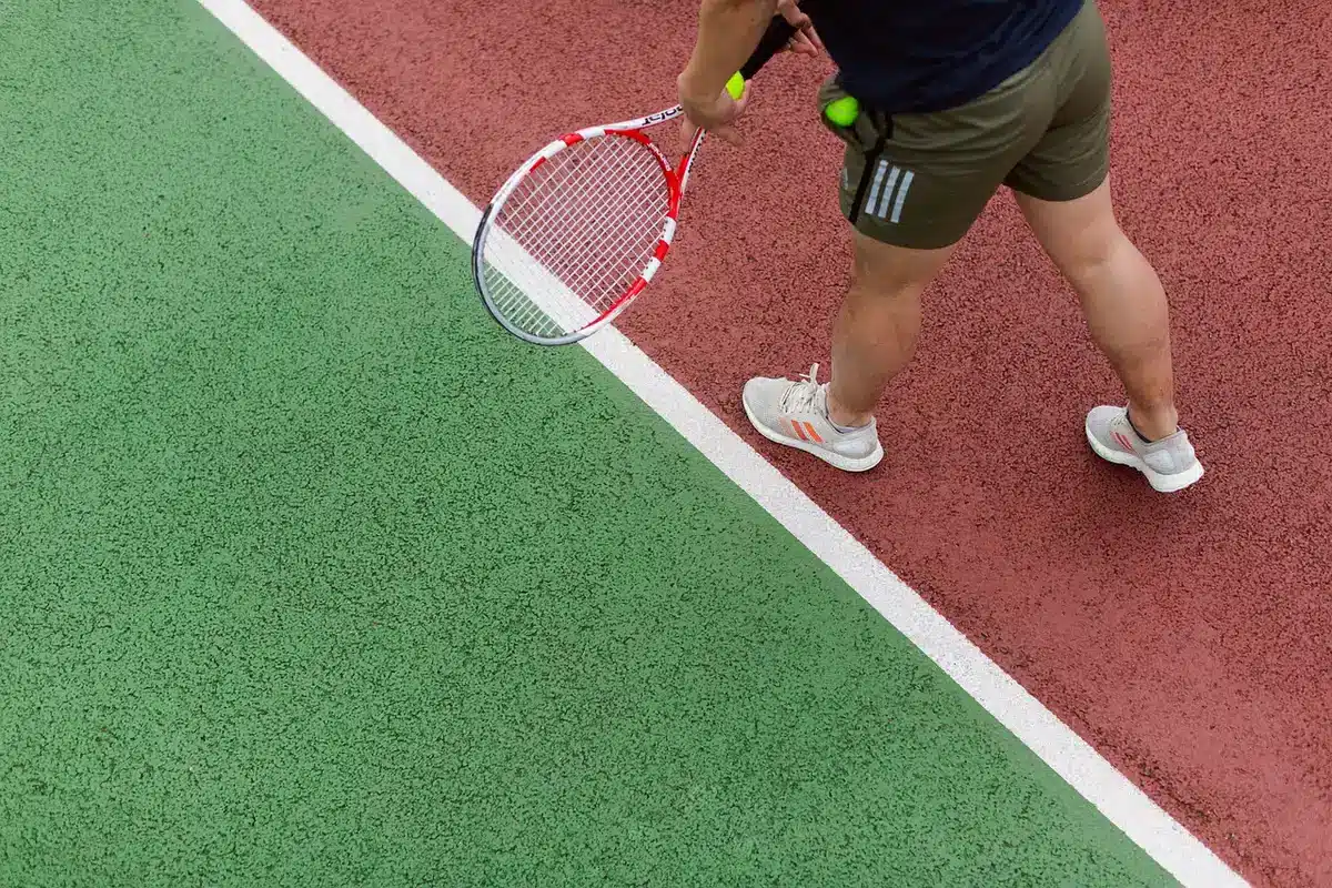Silhouette di giocatore che esulta su campo da tennis, pubblico sfocato