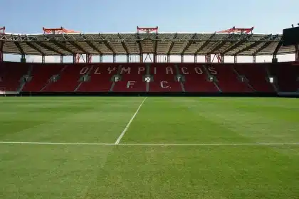 Stadio vuoto con sciarpa giallorossa e pallone in primo piano