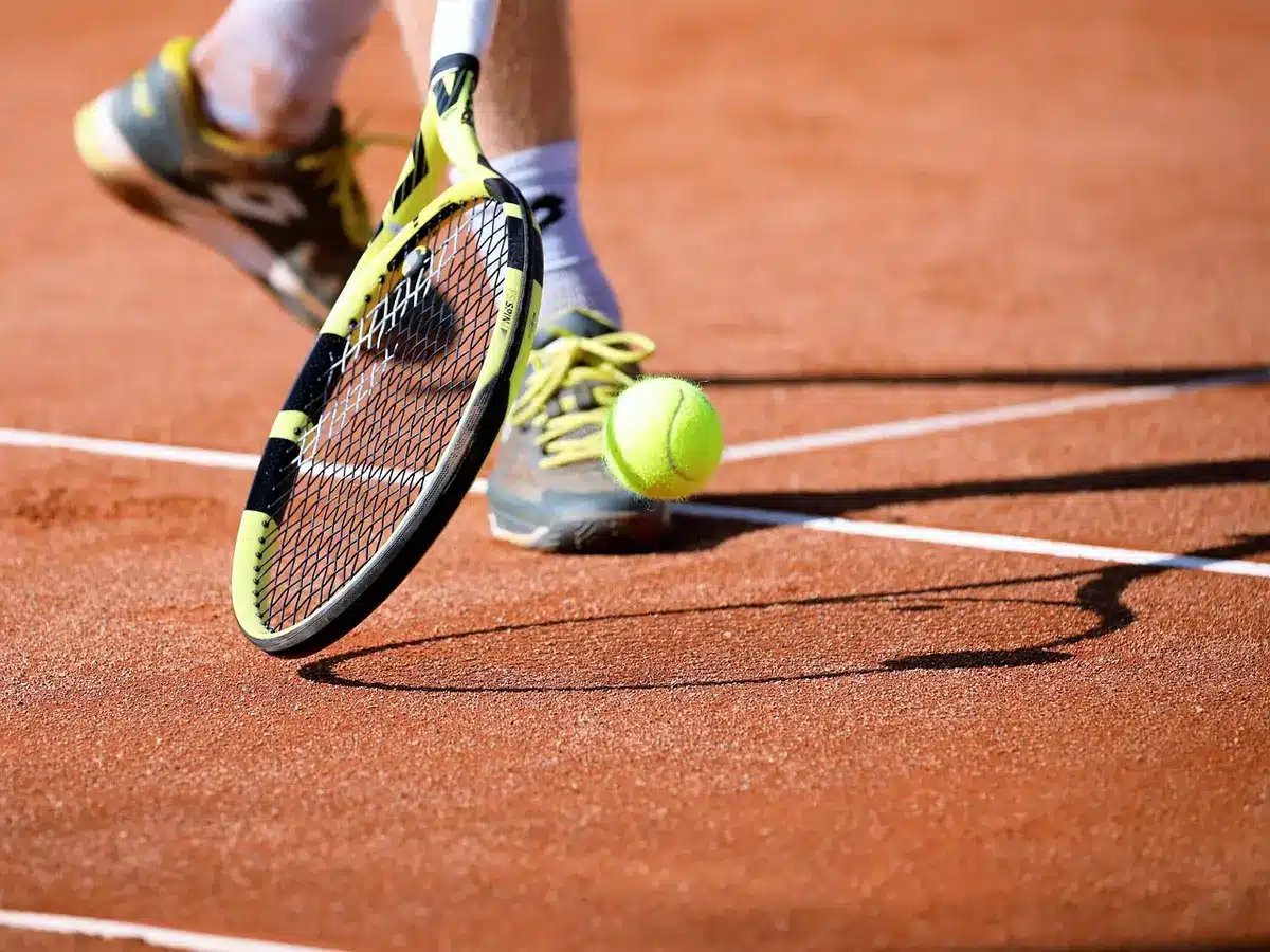 Campo da tennis vuoto con racchetta appoggiata al cancello e asciugamano, atmosfera pensosa